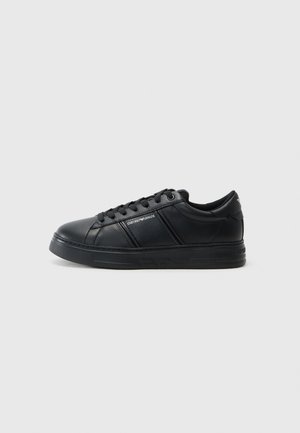 Zwarte leren sneaker met een gladde afwerking, ronde neus, vetersluiting aan de voorkant, gevoerde kraag en getextureerde zijaccenten. Subtiele logo-detail zichtbaar.