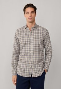 Camisa de manga larga a cuadros para hombre en beige, azul marino y marrón. Presenta un cuello tipo button-down y un corte relajado con un dobladillo curvado.