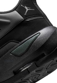 Sneaker nera con una tomaia texture, accenti lisci e un dettaglio verde di lato. Include una suola in gomma con un battistrada pattern.