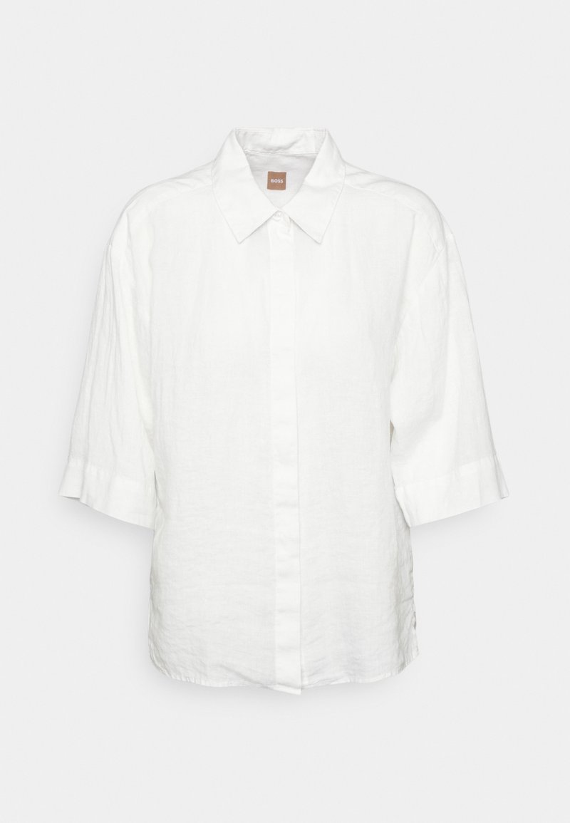 Chemise blanche à manches courtes en lin, dotée d'une patte de boutonnage à l'avant, d'un col classique et d'une coupe décontractée. Aucun motif ni élément métallique visible.