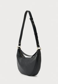 Sac à bandoulière en cuir noir à la forme incurvée, avec des accents en métal doré, une bandoulière réglable et une poche zippée pour un rangement sécurisé.