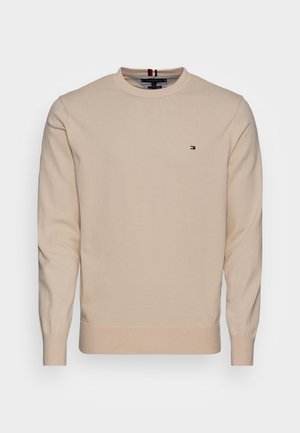 Beige Baumwollpullover mit langen Ärmeln, Rundhalsausschnitt, gerippten Bündchen und Saum, mit einem kleinen Logo in Rot, Weiß und Blau auf der Brust.