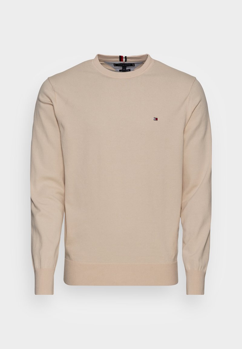 Maglione in cotone beige con maniche lunghe, scollo rotondo, polsini e orlo a costine, con un piccolo logo rosso, bianco e blu sul petto.