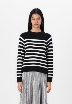 Maglione a righe bianche e nere con scollatura rotonda e bordo a coste, abbinato a una gonna plissettata metallica.