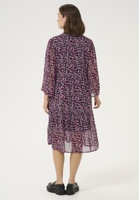 Long, purple floral dress with a sheer texture, 3/4 sleeves, and a tiered hem. Paired with black platform shoes.