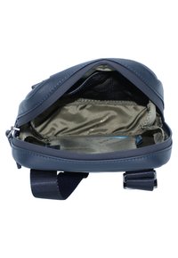 Borsa a tracolla in pelle blu navy con un ampio scomparto principale che rivela un rivestimento liscio di colore chiaro e accessori per la regolazione della tracolla.