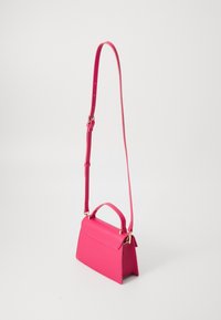 Różowa skórzana torebka o wyraźnie zarysowanym kształcie, z krótkim uchwytem i regulowanym paskiem do noszenia na ramieniu. Elementy wykończone w złotym odcieniu.