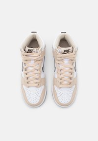 White and beige high-top sneakers with perforated toe, textured panels, flat laces, and a logo on the tongue.