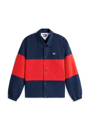 Giacca stile coach blu navy e rossa con bottoni a pressione, polsini elastici e piccolo logo Tommy Jeans sul petto sinistro.