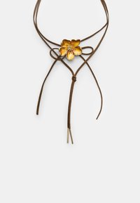 Ogrlica iz rjavega semiša z zapletenim zlatenim cvetličnim osrednjim delom, ki ima podrobne cvetne liste in dva tanka vrvica z metalnimi konicami.