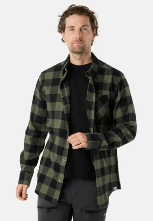 Schwarz-grün karierter Flanellhemd, knopfbares Design mit langen Ärmeln, ausgestattet mit einer Brusttasche und strukturiertem Stoff. Darunter ein schwarzes T-Shirt.