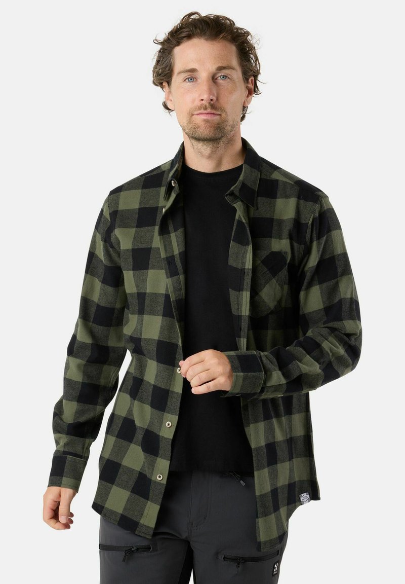 Zwart en groen geruite flanellen overhemd, met een knoopsluiting en lange mouwen, voorzien van een borstzak en textuurstof. Zwarte T-shirt eronder.