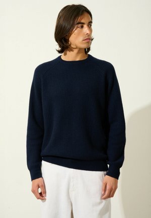 Maglione a coste navy con scollo rotondo e maniche lunghe. Presenta una vestibilità rilassata e un tessuto testurizzato. Abbina a pantaloni di colore chiaro.