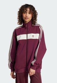 Maroon athletic jacket with white horizontal stripe and three white stripes on sleeves; full zip design and fabric texture is smooth.