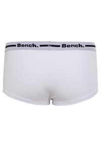 Biele bavlnené boxerky s úzkym šedým pásom, na ktorom je čierny nápis "Bench." Hladká textúra a priliehavý strih.
