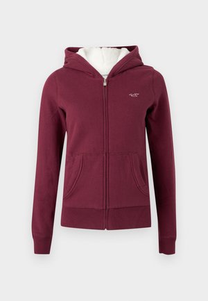 Vinrød hettejakke med glidelås laget av mykt stoff, med en foret hette, to fremre lommer og brodert logo på brystet.