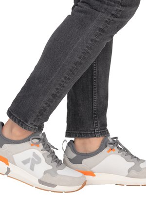 Gray and white athletic sneakers with a textured design, featuring orange accents and light gray suede panels, shown with gray jeans.