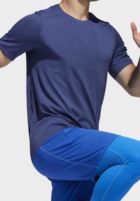 Námořnické tričko s krátkým rukávem a texturovanou tkaninou, kulatým výstřihem, spárované s modrými sportovními šortkami s hladkým, elastickým designem.
