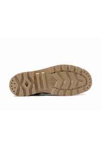 Semelle de chaussure en caoutchouc brun avec un motif de semelle texturé comportant des rainures irrégulières et des sections surélevées pour une meilleure adhérence.