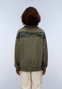 Sudadera verde oliva con un corte relajado, que presenta un patrón abstracto en verde oscuro en la parte superior de la espalda, y "Napapijri geographic" impreso debajo.