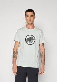 Light mint green cotton t-shirt featuring a large black mammoth graphic in a circular outline, with a crew neckline and short sleeves.