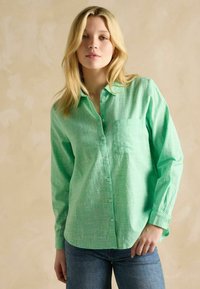 Mintgroene button-up shirt met een gestructureerde stof, voorzien van een borstzak en lange mouwen, gecombineerd met blauwe denim jeans.