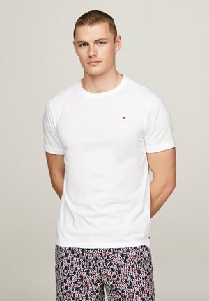 Witte katoenen t-shirt met korte mouwen, ronde hals en een klein geborduurd logo. Gecombineerd met gestipte shorts met een herhaald tekstontwerp.