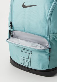 Nike rygsæk i teal med grå detaljer. Har et stort rum, lynlåslomme, mesh sidelomme og sort bund. Tekstureret materiale.