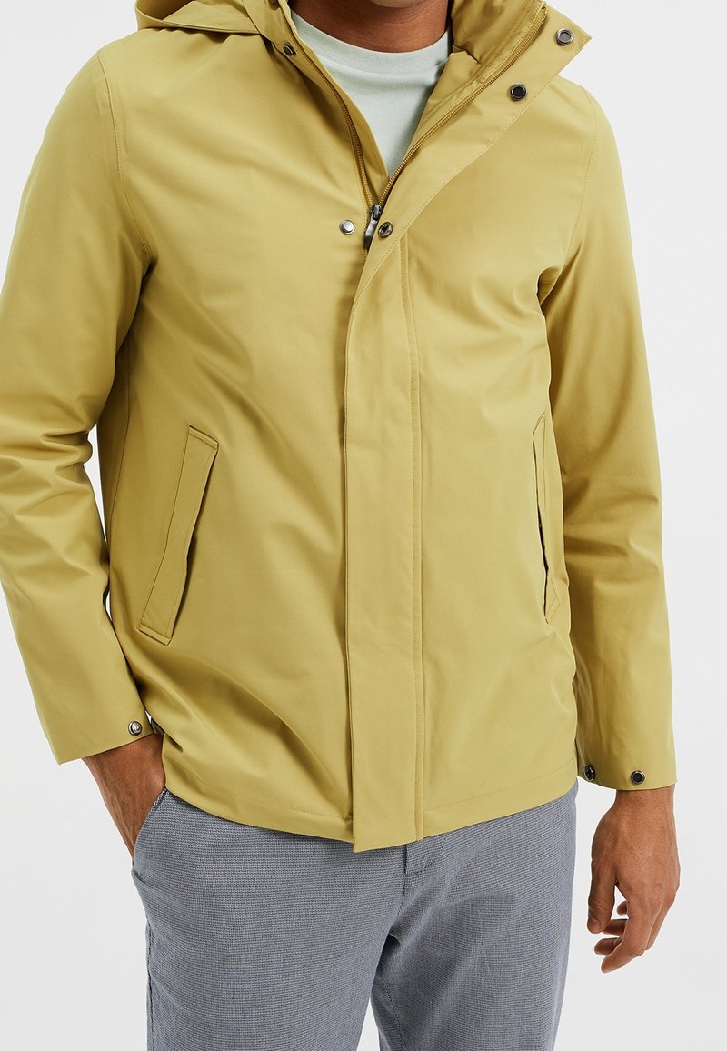 Yellow waterproof jacket with a hood, featuring snap buttons, zip closure, and side pockets. Smooth texture and fitted design.