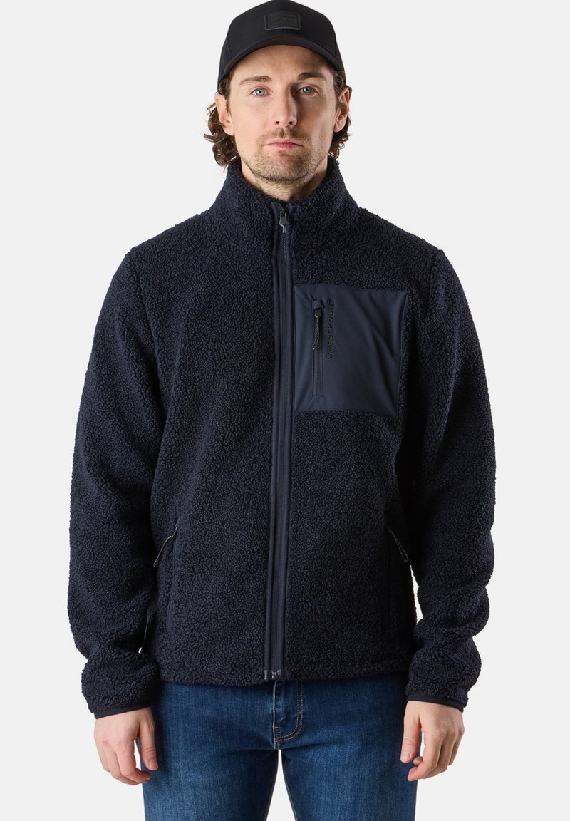 Giacca in pile navy con zip frontale, colletto alto e tasca sul petto. Presenta un esterno testurizzato e dettagli lisci.