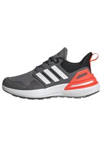 Zapatilla deportiva gris con parte superior de malla, tres franjas blancas, suela de goma y un acento naranja en el talón. Cuenta con puntera redondeada y plantilla acolchada.