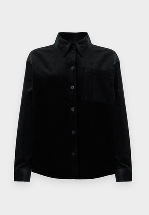 Chemise en velours côtelé noire à manches longues, avec un col classique, une fermeture à boutons sur le devant et une poche poitrine. Présente une texture côtelée sur l'ensemble.