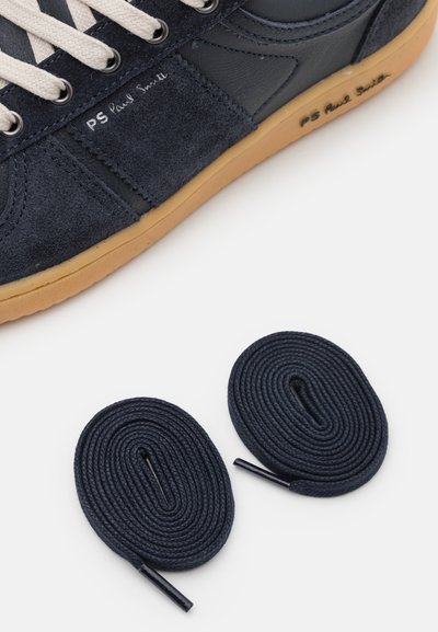 Marineblå mokka- og lærk sneaks med kremfargede lisser og gummisåle; inkluderer to marineblå runde lisser med plastspisser. "PS Paul Smith" trykt på siden.