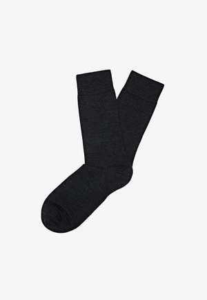 Calzini neri realizzati in un morbido tessuto a maglia. Presentano un tallone e una punta rinforzati, un design con polsino a coste e una texture liscia in tutto il calzino.