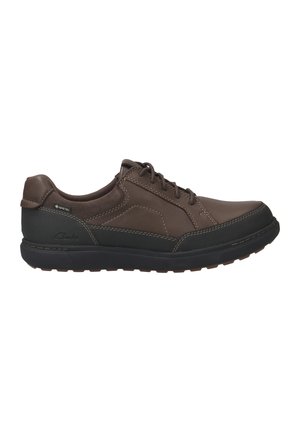 Brown leather shoe with a black rubber sole, featuring lace-up design and waterproof Gore-Tex detail. Smooth texture, padded collar.