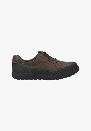 Brown leather shoe with a black rubber sole, featuring lace-up design and waterproof Gore-Tex detail. Smooth texture, padded collar.