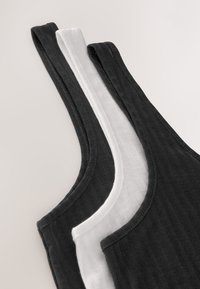 Tre tanktops i sort og hvid med en ribbet tekstur, brede stropper og blødt buede kanter. Tydelige syninger som detaljer.