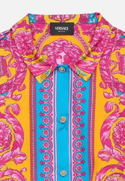 Šarena Versace košulja s uzorkom u žutoj, ružičastoj i plavoj boji s motivima cvijeća, strukturiranim ovratnikom i srebrnim gumbima sprijeda.