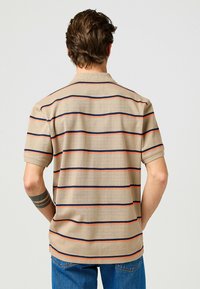 Beige randig polo-tröja med horisontella linjer i marinblått och orange. Kort ärm, krage och mjukt material synligt bakifrån.