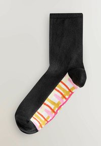 Schwarze Socke mit gemustertem Fuß, der gelbe, pinke und orange abstrakte Linien auf weißem Hintergrund zeigt. Durchgehend gerippte Struktur.