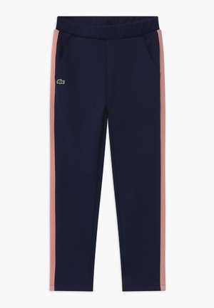 Pantalon de sport bleu marine avec des bandes latérales roses, une ceinture élastique, des poches latérales et un petit logo crocodile vert sur la cuisse gauche.