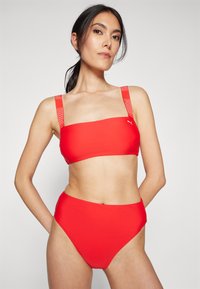 Červený bikiny set s bandeau topom so širokými ramienkami a hornou časťou so zvýšeným pásom, vyrobený z hladkej elastickej tkaniny s minimálnym zdobením.