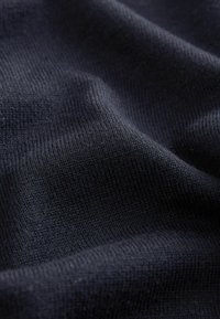 Tessuto lavorato a maglia blu navy, caratterizzato da un fine motivo a coste, morbido e liscio con una leggera lucentezza, che evidenzia la profondità delle pieghe e delle creste.