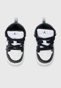 Baskets noir et blanc avec une tige en cuir, bout rond, avant perforé, lacets noirs et une languette de talon grise. Affiche le logo Jordan.