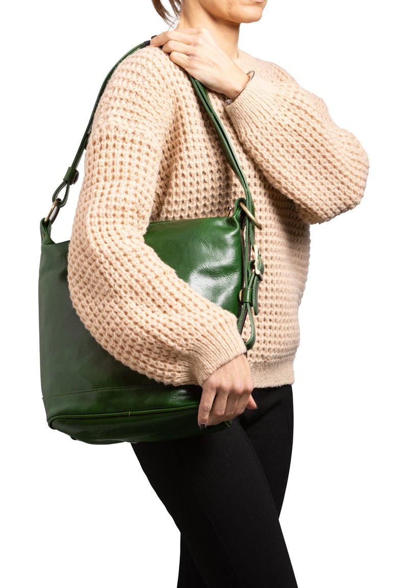 Groene leren handtas met een gladde textuur, voorzien van een schouderriem en gouden hardware accenten. Draagt over een beige trui.