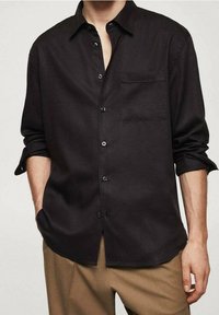 Chemise noire à manches longues en tissu léger, avec une poche, un devant boutonné et une coupe décontractée, présentée sur un fond neutre.