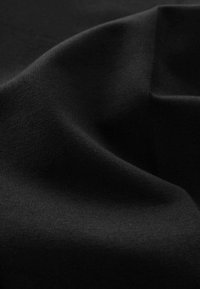 Schwarzer Stoff mit glatter Textur, der Falten und Knitter aufweist, die das weiche, matte Finish betonen. Das Material scheint dehnbar zu sein.