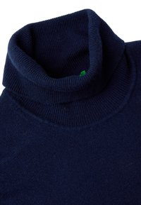 Maglione a collo alto di colore blu navy con texture a coste. Presenta un ampio colletto pieghevole e un piccolo tag verde integrato nel tessuto.