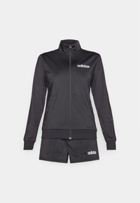 Μαύρο σετ τζάκετ και σορτς Adidas. Το τζάκετ διαθέτει φερμουάρ, ψηλό γιακά και άσπρο λογότυπο. Τα σορτς είναι ελαστικά και απλά στο σχέδιο.