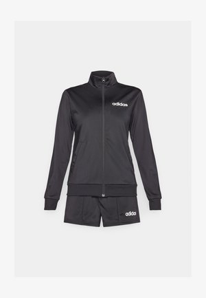Set giacca e pantaloni corti Adidas neri. La giacca presenta una chiusura con zip, un colletto alto e il logo bianco; i pantaloni corti sono elastici e di design semplice.